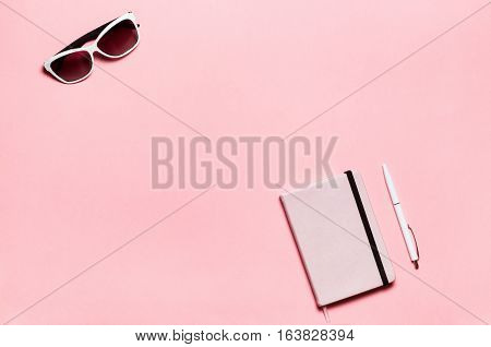 Pink diary, white pen, glasses on pink textplace background. flat lay, top view. Feminine workspace.