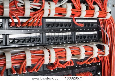 Server rack with red internet patch cord cables connected to patch panel in server room