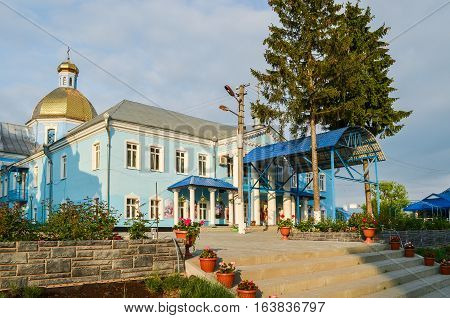 Gorodok, Ukraine - May 14, 2013: Blue colored orthodox church in small town in Rivne oblast or region with gold cupola and flower pots
