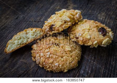 Homemade cornflakes and raisins cookies on old wooden table. Freshly baked corn flake cereal cookies on rustic background. Selective Focus.