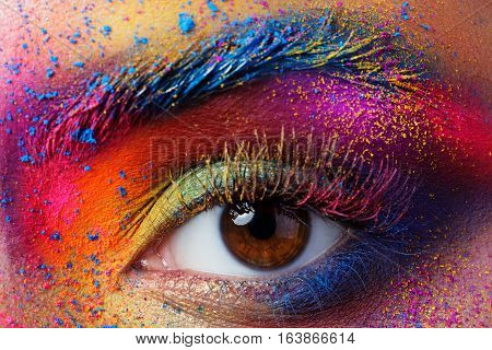 Close up view of female eye with bright multicolored fashion makeup. Holi indian color festival inspired. Studio macro shot