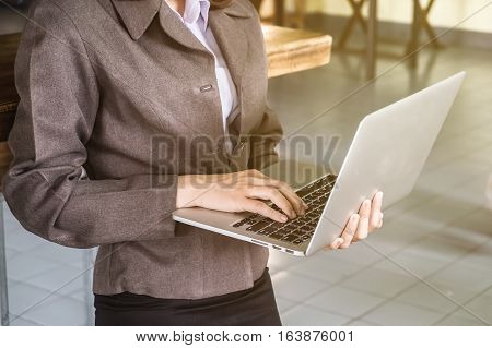 Business woman standing and hand holding notebook for using laptop computer.