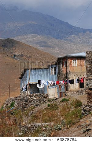 Xinaliq, Azerbaijan - August 23, 2014. Residential house in Xinaliq village, with linen put out to dry and mountains in the background.