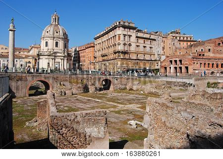 Rome, Italy - October 9, 2014. View of Trajan Forum in Rome, with Roman ruins, Trajan Column, Chiesa SS Nome di Maria, surrounding buildings and people.