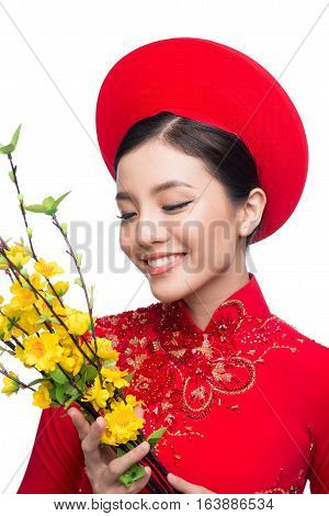 Portrait of a beautiful Asian woman on traditional festival costume Ao Dai holding Hoa Mai tree (Ochna Integerrima) flower. Tet holiday. Lunar New Year.