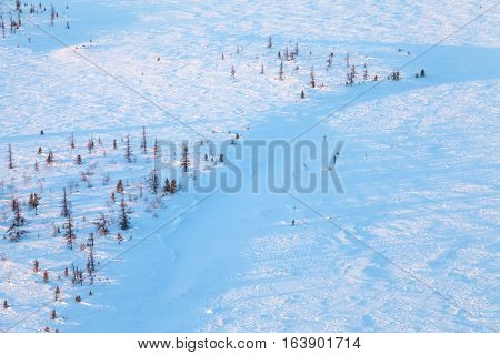 Aerial view above the snow covered tundra in time of short winter day.