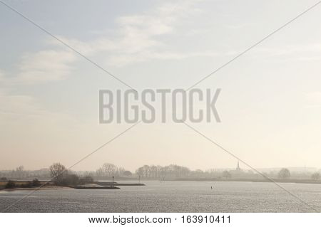 part of river Lek ands silhouette of dutch town Lexmond in province of South-Holland in the netherlands