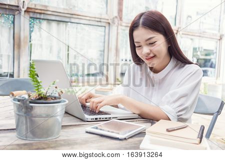 young happy casual asian woman using technology on her laptop computer and looking at her tablet