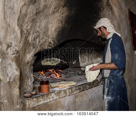 NAZARETH ISRAEL - DECEMBER 16: Man dressed in period clothes bakes bread in Nazareth Village Israel on December 16 2016