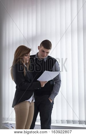 Two business colleagues analyzing financial report charts in an office