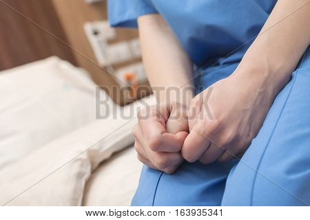 A patient's hands squeezing thumbs with hope in a modern hospital.