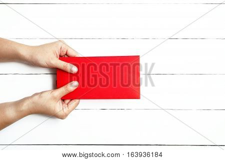 Red Envelope or red packet for Chinese New Year Gifts held in hand on the white wooden plank background Traditional Celebration Chinese New Year.