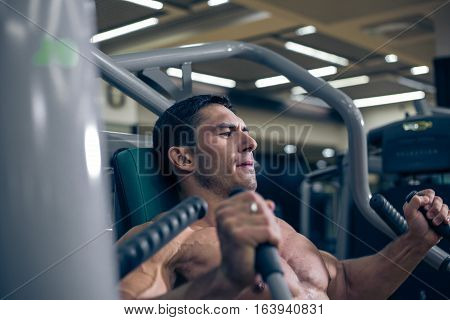 Bodybuilder doing hard exercise. Hard work in trenadernom hall. Severe look. Man swinging. Serious look. Focused on results.