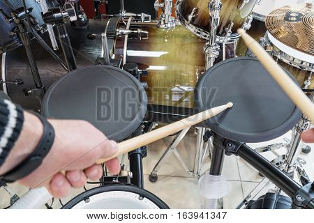 Hands drummer drumsticks knock on the black electric drum, close-up in the first person