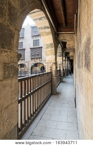 Angled view of one arch with interleaved wooden balustrades at the arcade surrounding the courtyard of caravansary (Wikala) of Bazaraa Medieval Cairo Egypt