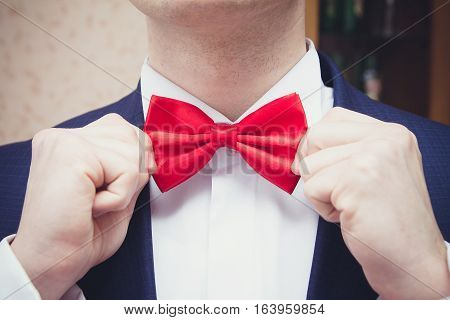 Elegant man corrects his hands red butterfly