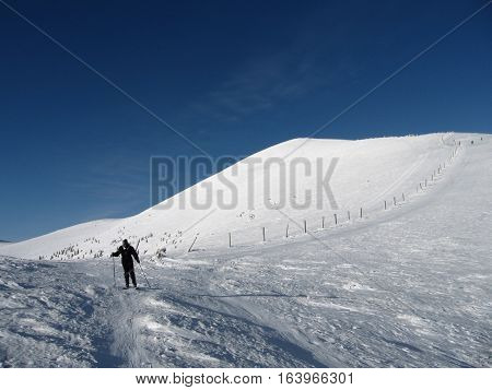 A skier on a long snow-covered road in the mountains ski resort