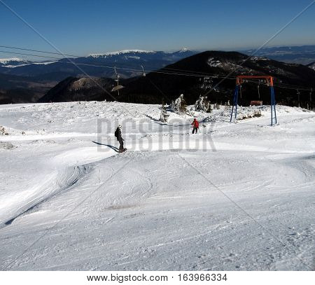 Snowboarder descends and rises to the skier lifts on snowy road