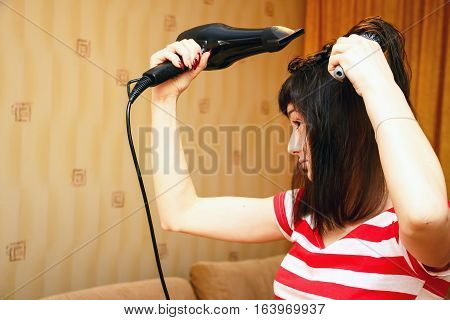 Girl dries hair and makes the hairstyle in her room. She uses the Hairdryer and comb. The home interior 5