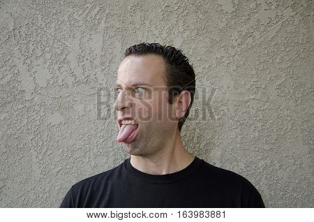 Funny face - man sticking his tongue out off to the left side.