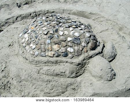 Sandcastle of a sea turtle made of sand and seashells
