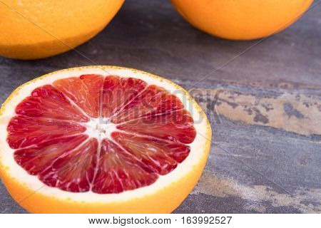 Blood oranges on gray slate with black background