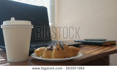 A Businessmans Desk With A Disposable Cup For Coffee And Fast Food. Open Laptop Computer. Breakfast 