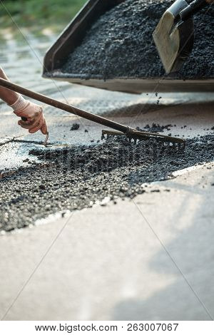 Closeup View Of Worker Paving The Road With Asphalt As They Level The Cement Mix.