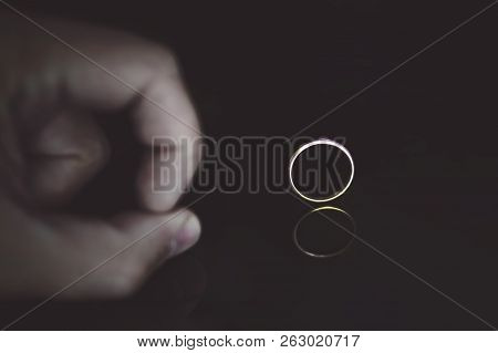 Close Up Of Mans Fingers On The Reflecting Black Surface Pushing On The Wedding Ring At The Black Ba