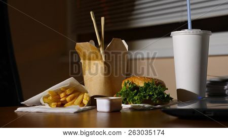 A Businessmans Table With A Disposable Cup For Coffee And Fast Food. Open A Laptop. Late Dinner At T