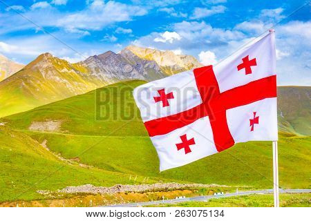 Beautiful View To Waving Flag Of Georgia On The Georgian Military Road Against The Background Of The