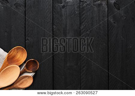Top Of Wooden Spoons And Dishtowel On Black Wooden Background With Copy Space. Top View Of Kitchen U