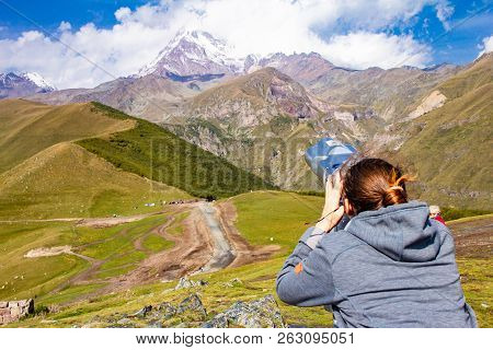 Girl Looking In Binoscope Directed Towards The Snowy Mountain Tops Of Kazbeg From The View Point Ger