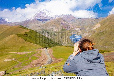 Girl Looking In Binoscope Directed Towards The Snowy Mountain Tops Of Kazbeg From The View Point Ger