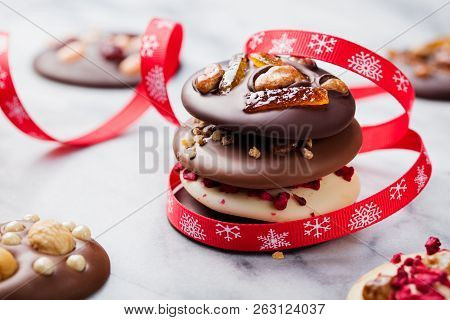 Chocolate Mediants, Bites, Candies With Christmas Ribbon On Marble Table Background. Close Up