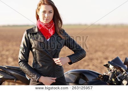 Travelling On Bike. Serious Beeautiful Cool Motorcyclist Zips Black Leather Jacket, Has Red Bandana 