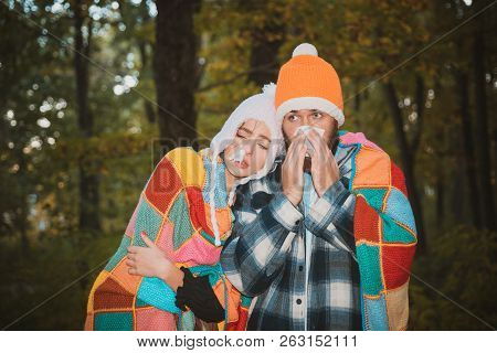 Showing Sick Couple Sneezing At Autumn Park. Girl With Handkerchief And Sneezing Boy In Autumn Park.