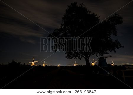 These Beautiful Windmills In Kinderdijk Are Illuminated With White Light At The Blue Hour