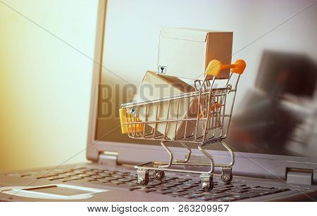 Cardboard Boxes Are In Trolley On Laptop. Idea For Online Shopping And E-commerce, Consumers Can Buy