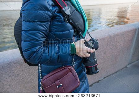 Photographer In The Street Photo Shooting Process. Model Is Young Lady In Stylish Black Coat With Bl