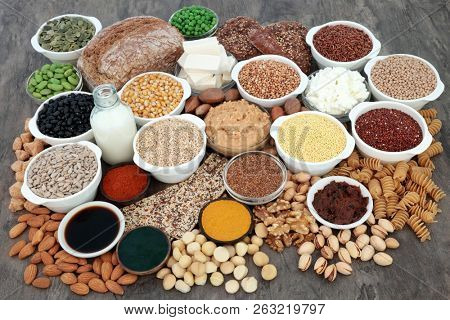 Large vegan health food with tofu bean curd, legumes, nuts, seeds, cereals, vegetables, pasta, bread, grains, almond butter, milk and yoghurt. High in antioxidants, omega 3, protein and dietary fibre.