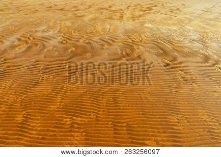 Beach Of Yellow Sand With Waves At Low Tide On A Sunny Day