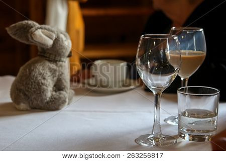 Glass With Irish Creme Liqueur, Empty Glass, Glass With Water, Cofee Cup And Rabbit On The Table.