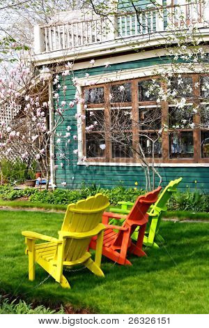 Fluorescentes cadeiras de jardim madeira rodeadas por magnólias floridas.