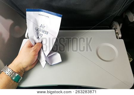 Passenger Holding Air Sickness Vomit Bag In Airplane