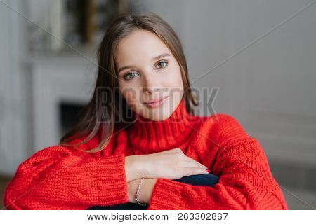 Caucasian Female With Make Up, Dark Hair, Dressd In Red Warm Swater, Looks Directly At Camera With C