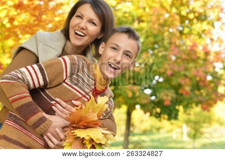 Portrait Of A Mother With Son Hugging Outoors In Autumnal Park