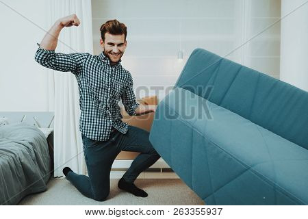 Young Male Moves A Big Sofa In The New Apartment. Reshuffle In The Room Concept. Domestic Problems. 