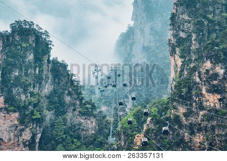 Famous tourist attraction of China - Zhangjiajie stone pillars cliff mountains in fog clouds with cable railway car lift at Wulingyuan, Hunan, China. With camera pan