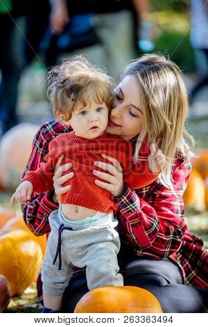 Young Mother With A Child On A Lawm With A Pumpkins. Autumn Season Time.